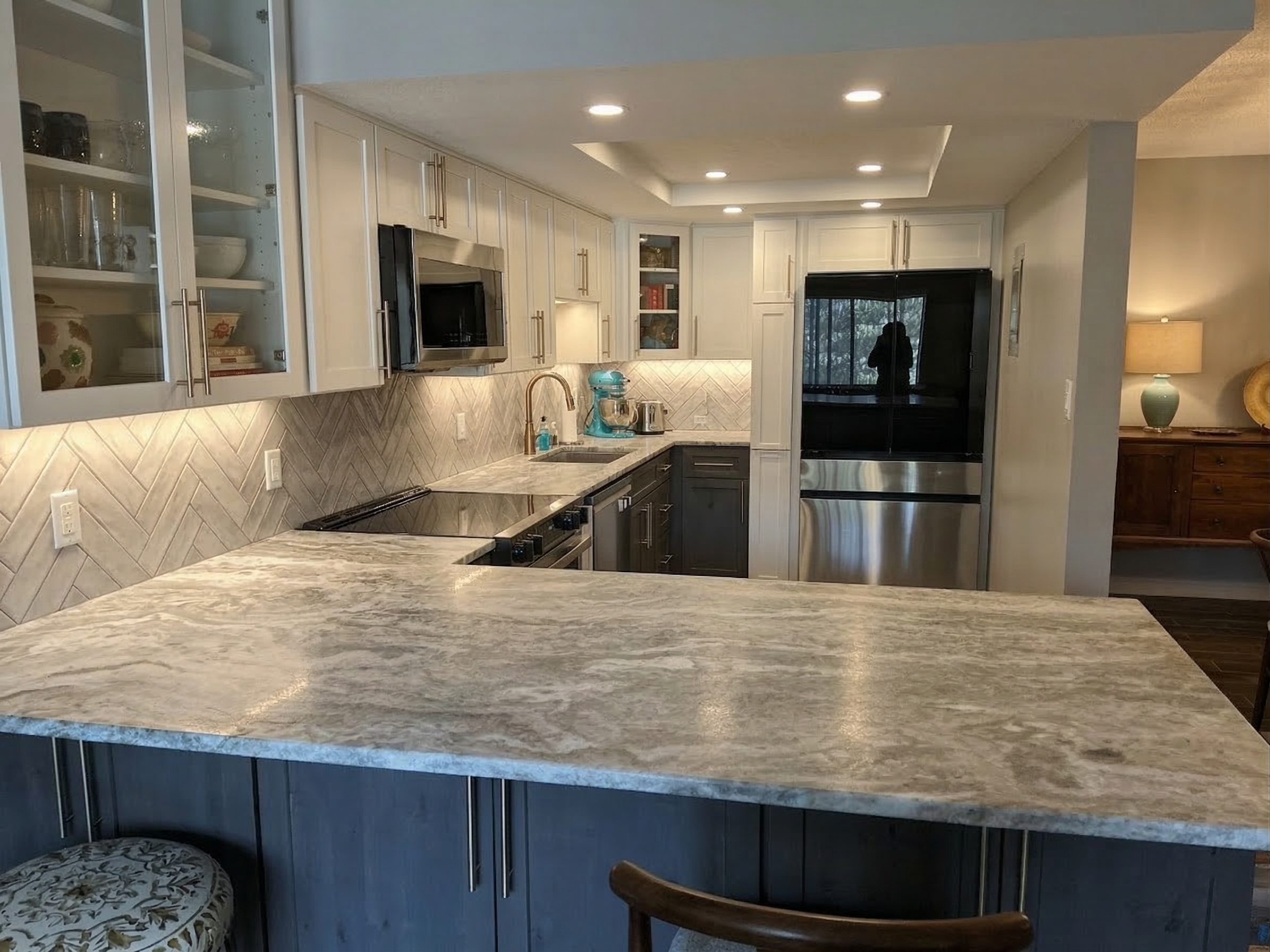 Renovated kitchen with marble counters and herringbone backsplash